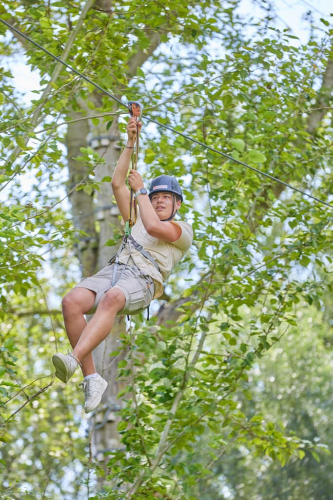 Jongvolwassene ziplined tussen de bomen.