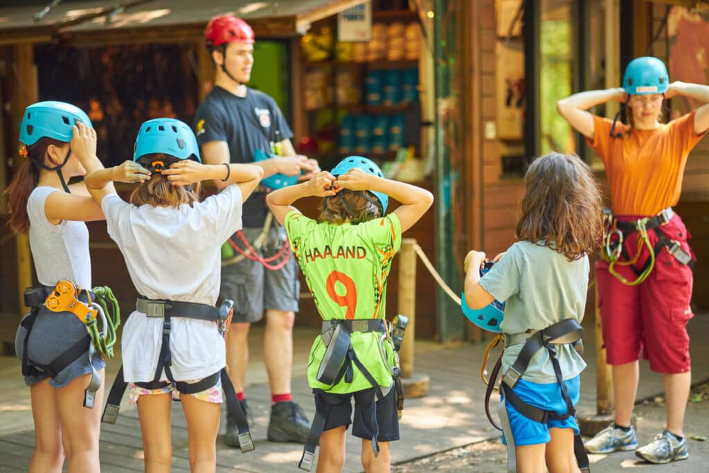 Fun Forest instructeur geeft instructie over hoe de helm opgedaan moet worden. De kinderen en volwassene volgen de instructie.