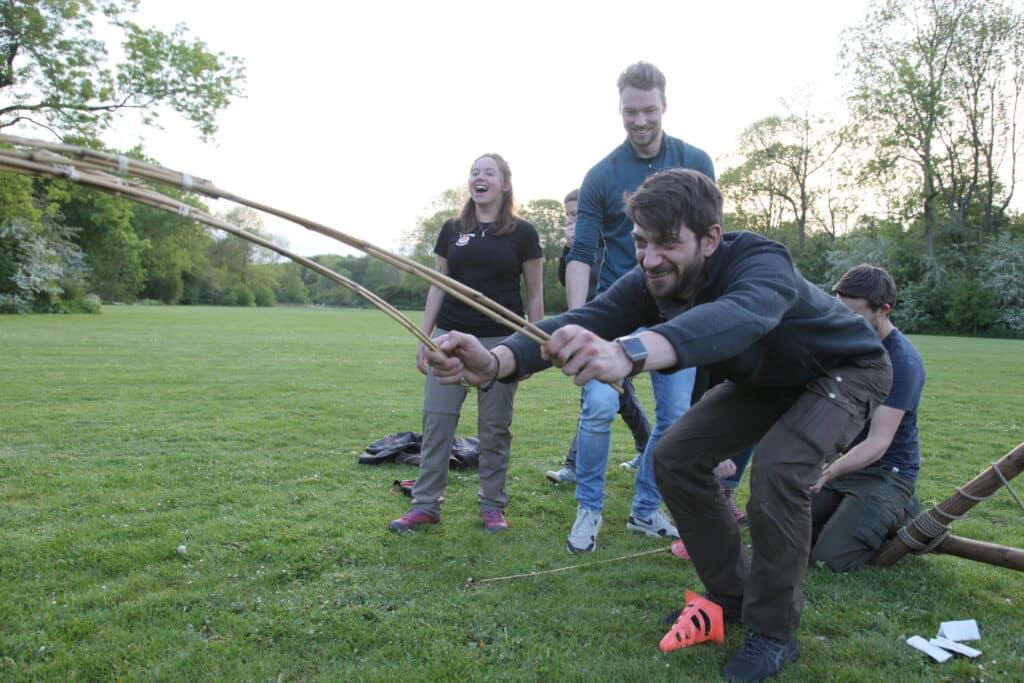 Meerdere mensen spelen een Expeditie spel met touwtjes en stokjes