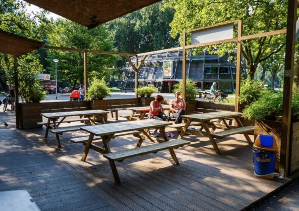 Terras bij Fun Forest Amsterdam met twee vrouwen die uitrusten. Op de achtergrond het Amsterdamse Bos en de Boswinkel.