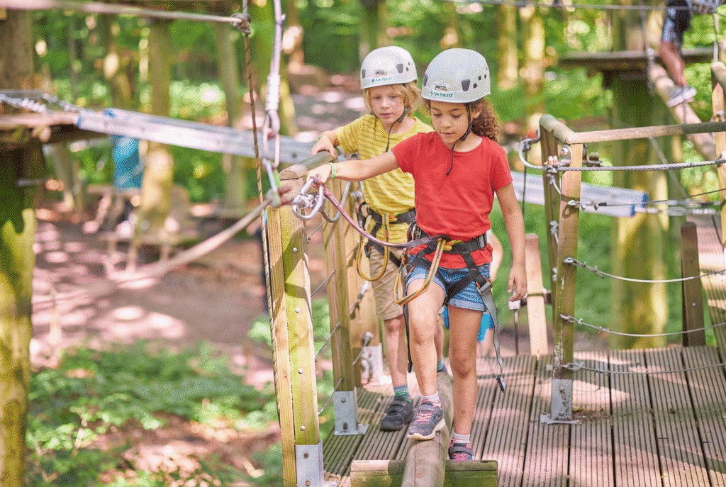 twee kinderen met een witte helm beginnen aan het eerste onderdeel van een parcours.